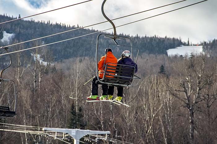 Skiers on Chairlift Over Trees in Maine