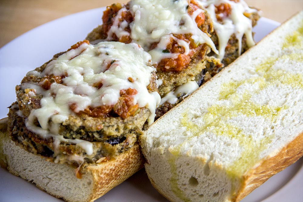 Placing Eggplant Parmesan on French Bread
